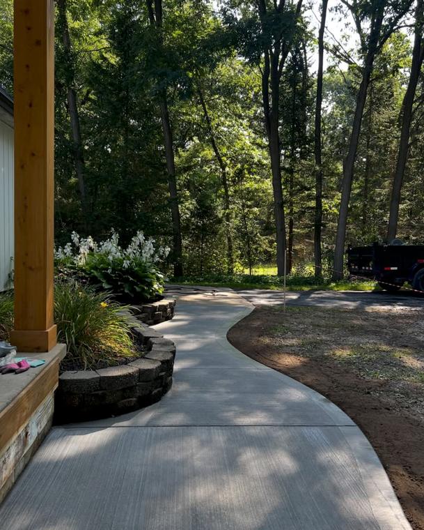 Broom-finished walk on a wooded lot — concrete work by Loaded Construction in metro Detroit