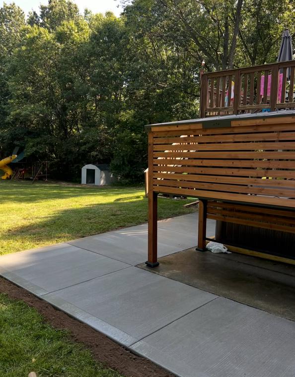 Patio slab beneath a raised deck and spa — concrete work by Loaded Construction in metro Detroit